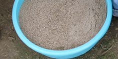 a person standing in front of a large blue bowl filled with sand on the ground