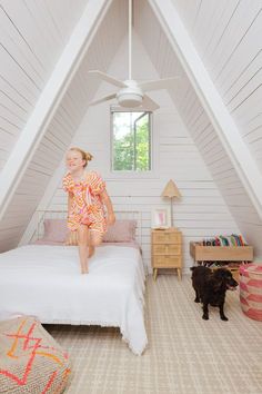 a woman sitting on top of a bed next to a black dog in a bedroom