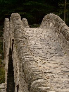 an old stone bridge with cobblestones going over it