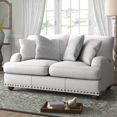 a living room with a white couch and some pillows on the floor in front of a window