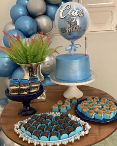 a table topped with cakes and desserts on top of a wooden table next to balloons