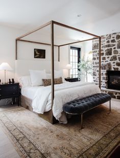 a bedroom with a four poster bed sitting on top of a rug next to a fireplace