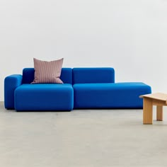 a blue couch sitting on top of a cement floor next to a wooden coffee table