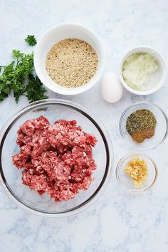 ingredients to make meatloaf laid out on a marble counter top, including eggs and seasonings