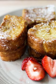 some strawberries are sitting on a plate next to french toast and powdered sugar