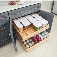 an open cabinet in a kitchen with food items on the bottom shelf and below it