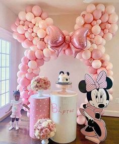 a minnie mouse balloon arch is decorated with balloons and other decorations for a birthday party