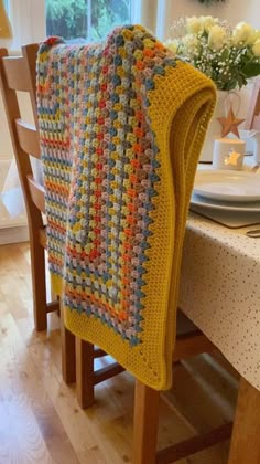 a crocheted blanket sitting on top of a wooden table next to a window