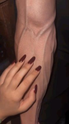 a woman with long nails holding her hand on the other side of her leg,