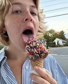 a woman eating an ice cream cone with sprinkles on it's tip