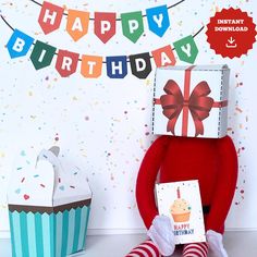 a red stuffed animal with a birthday card in front of it's face and two cupcakes on the ground