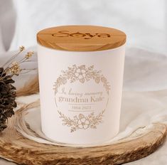 a white candle sitting on top of a wooden tray next to pine cones and flowers