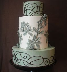 a three tiered cake decorated with flowers and swirls