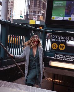 a woman is walking down the street with her hand in her pockets and holding onto an umbrella