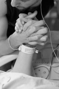 a man holding his hands together while listening to music on earphones in the hospital bed