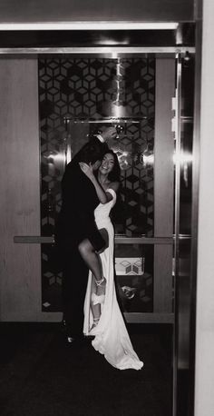 black and white photograph of a bride and groom kissing in front of an elevator door