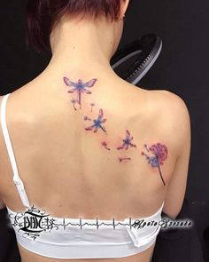 the back of a woman's neck with flowers and dragonflies on her shoulder