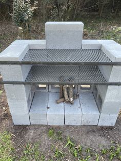 an outdoor fire pit made out of concrete blocks and steel grates with logs sticking out of it