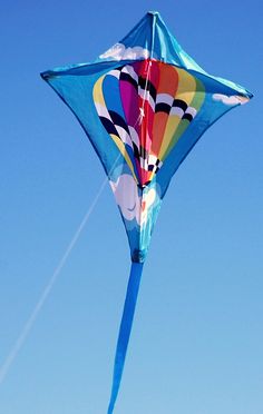 a colorful kite flying high in the sky on a clear day with blue skies behind it