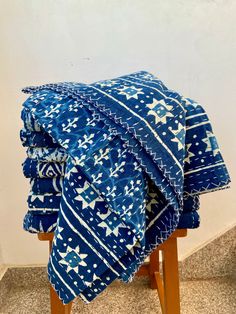 a blue and white blanket sitting on top of a wooden stool