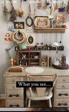 an old desk with lots of necklaces hanging on the wall and a sign that says, what you see?