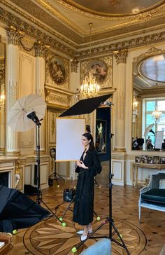 a woman is standing in front of a camera and recording something on a tripod