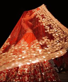 a woman in a red and gold dress is dancing with her veil over her head