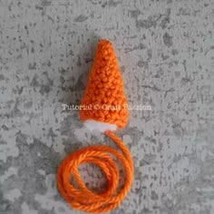 an orange crochet hat and rope on a gray surface