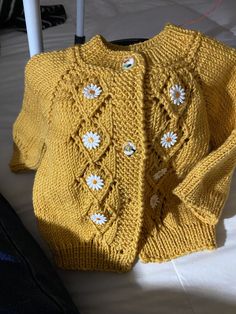 a yellow knitted sweater sitting on top of a bed