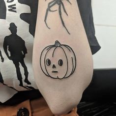 a spider and pumpkin tattoo on the arm