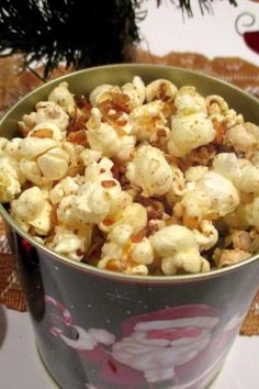 a tin filled with popcorn sitting on top of a table next to a christmas tree