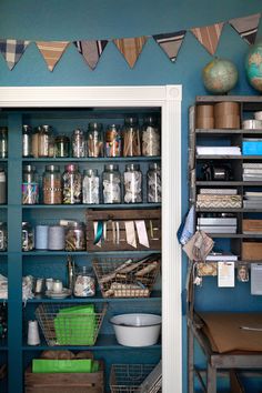 an organized pantry with lots of items on shelves and hanging from the ceiling in front of blue walls