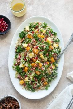 a white plate topped with salad next to two bowls filled with fruit and veggies