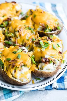 loaded baked potatoes with cheese and green onions on a white plate, ready to be eaten