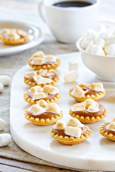 small desserts are arranged on a plate with marshmallows in the background