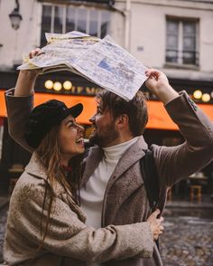 a man and woman are holding up maps in front of their heads while they look at each other