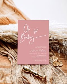 a pink card with the word oh baby written on it next to two gold coins