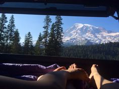 two people are laying down in front of a mountain