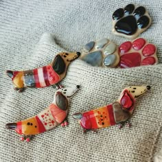 three dog brooches sitting on top of a white blanket next to each other