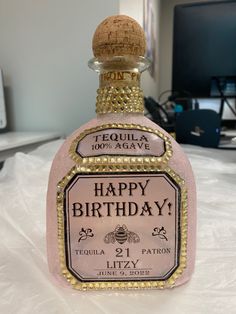 a bottle of tequila happy birthday sitting on top of a white tablecloth covered bed