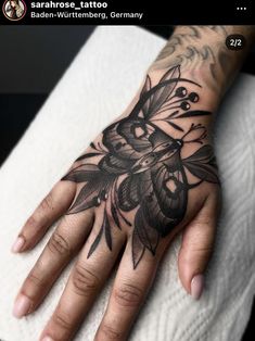 a person's hand with a tattoo on it and some flowers in the middle