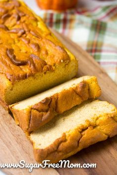 sliced loaf of pumpkin bread sitting on top of a wooden cutting board next to an orange pumpkin