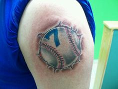 a baseball tattoo on the back of a woman's shoulder