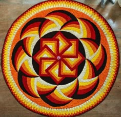 an orange and yellow circular design on a wooden floor