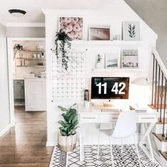 a desk with a computer on top of it next to a stair case and potted plant