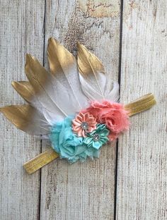 a white and gold feather headband with pink, blue and green flowers on it