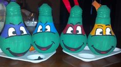 three green plastic bottles with faces painted on them, sitting on plates in front of a table