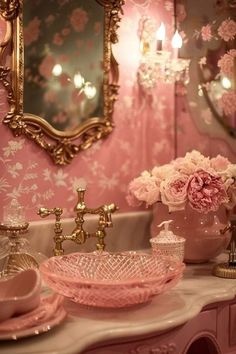 a bathroom with pink walls and floral wallpaper, gold mirror above the sink and antique faucet