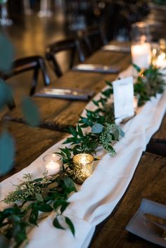 a long table with candles and greenery on it