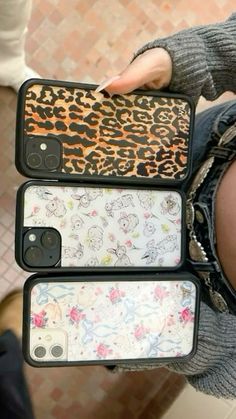 three cell phones sitting on top of each other in their cases, one with an animal print